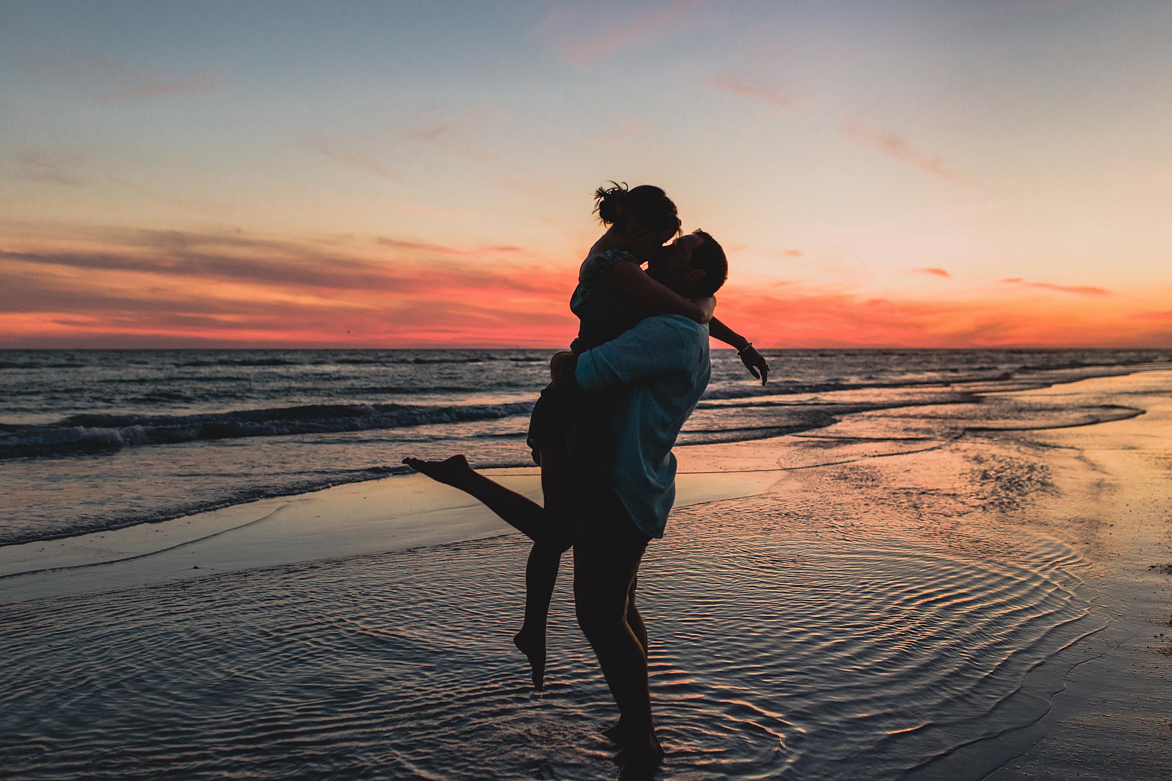couple embracing during sunset at engagement session on siesta key beach