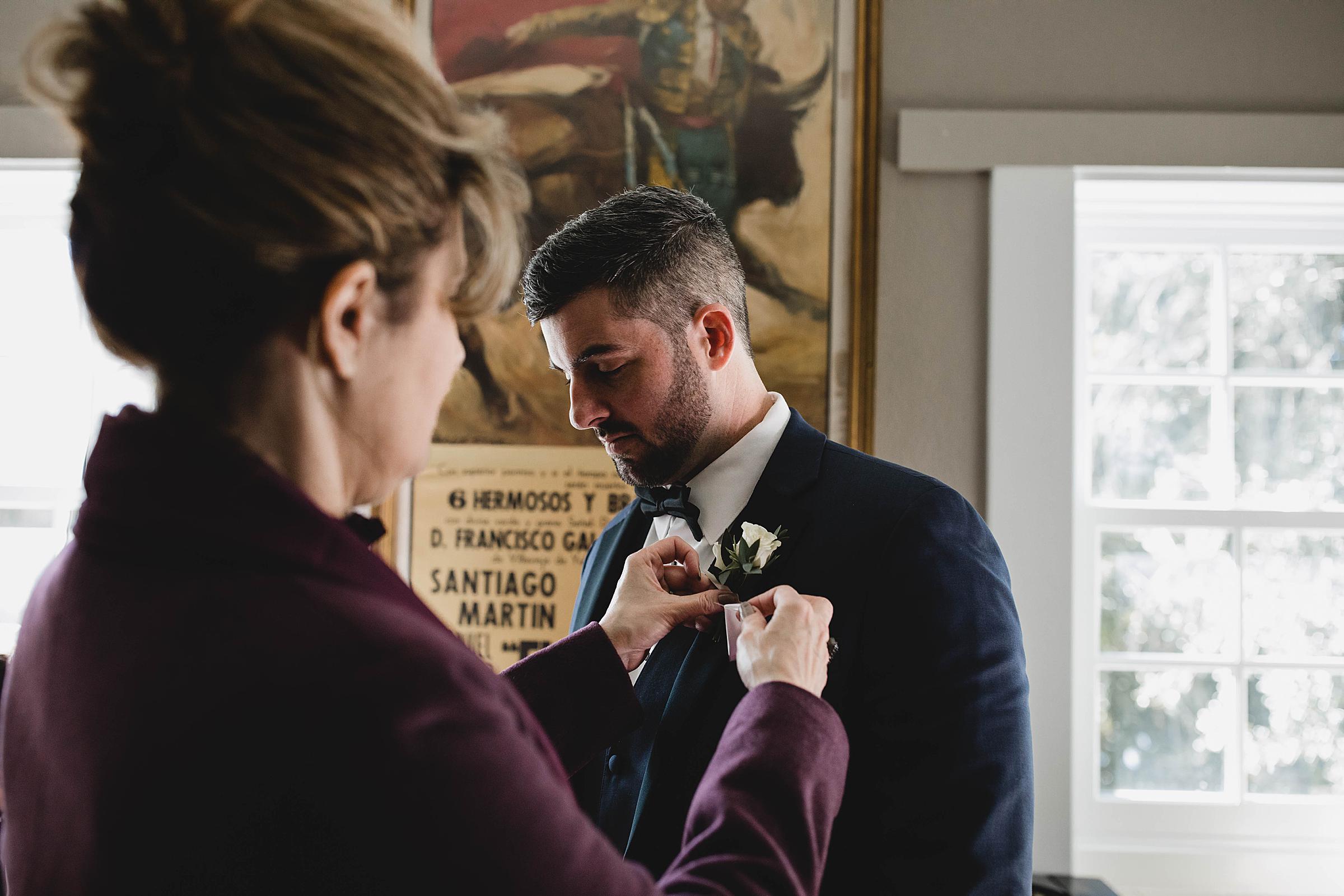 Mother of groom pinning her son's boutonniere at Selby gardens wedding in sarasota, photographed by Juliana Montane Photography