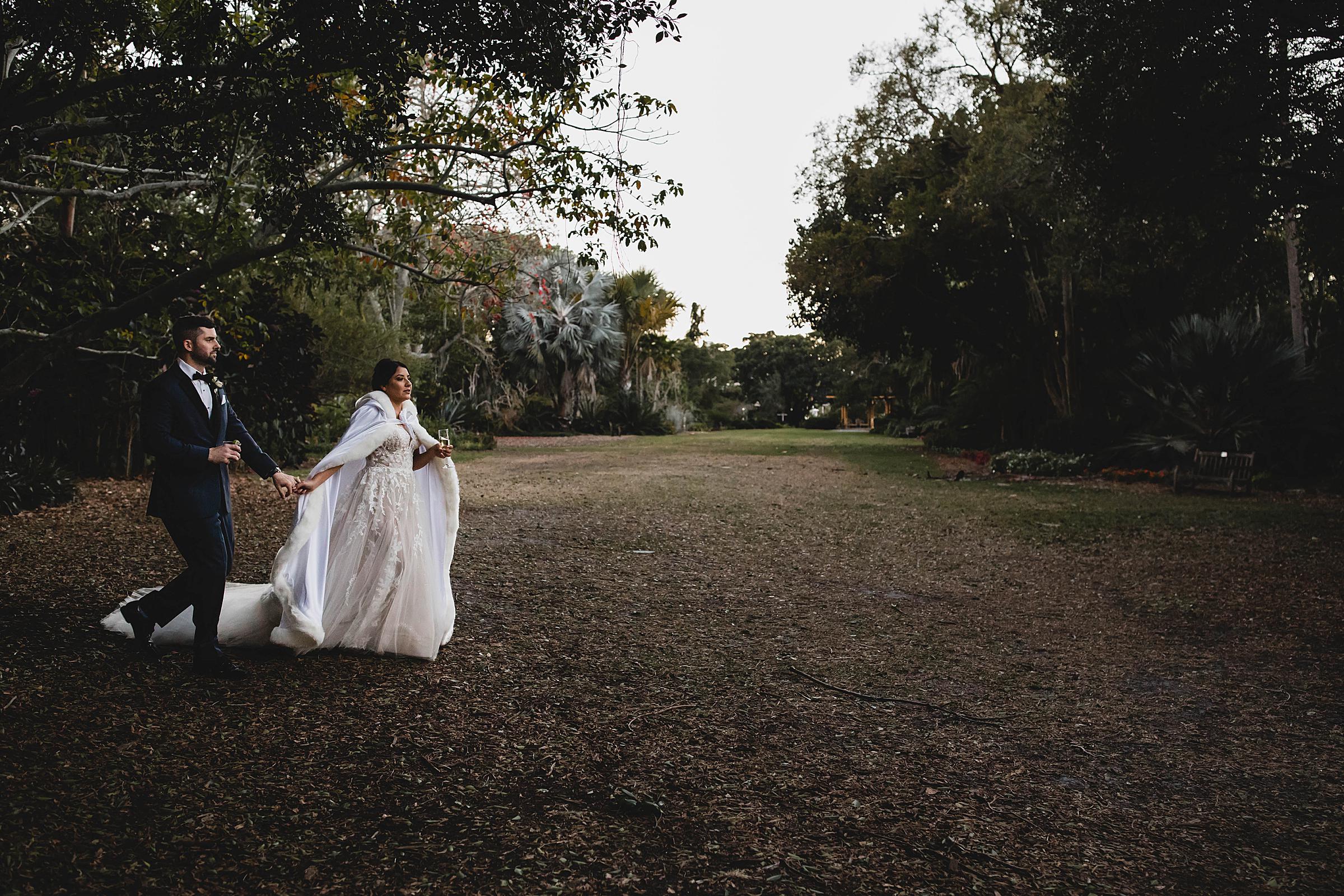 married couple walking across the great lawn at Marie Selby Botanical Gardens, Selby gardens wedding photographer