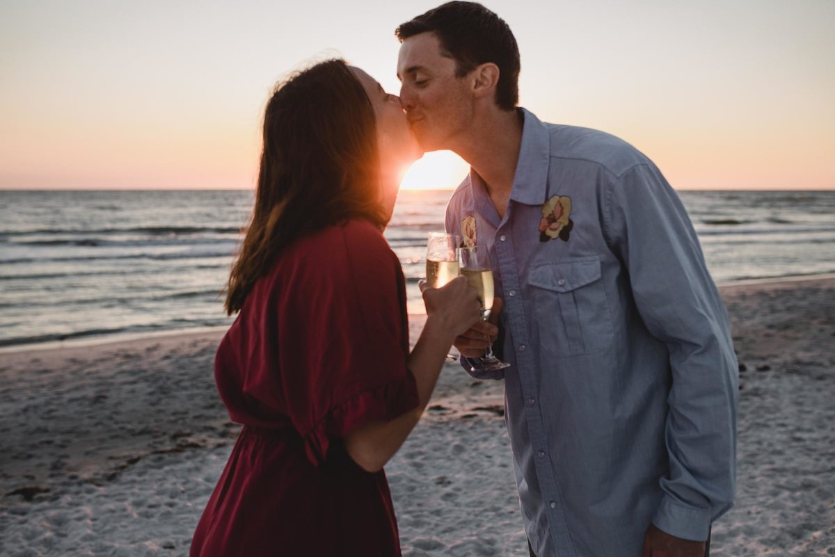 couple kissing with champagne at longboat key florida engagement photography session