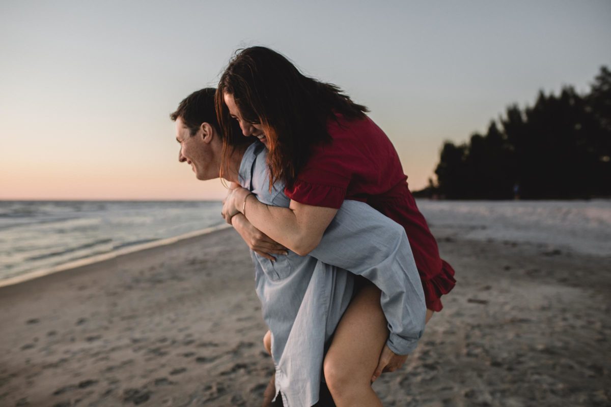 guy carrying girl on his back at the beach on longboat key florida engagement session by juliana montane photography