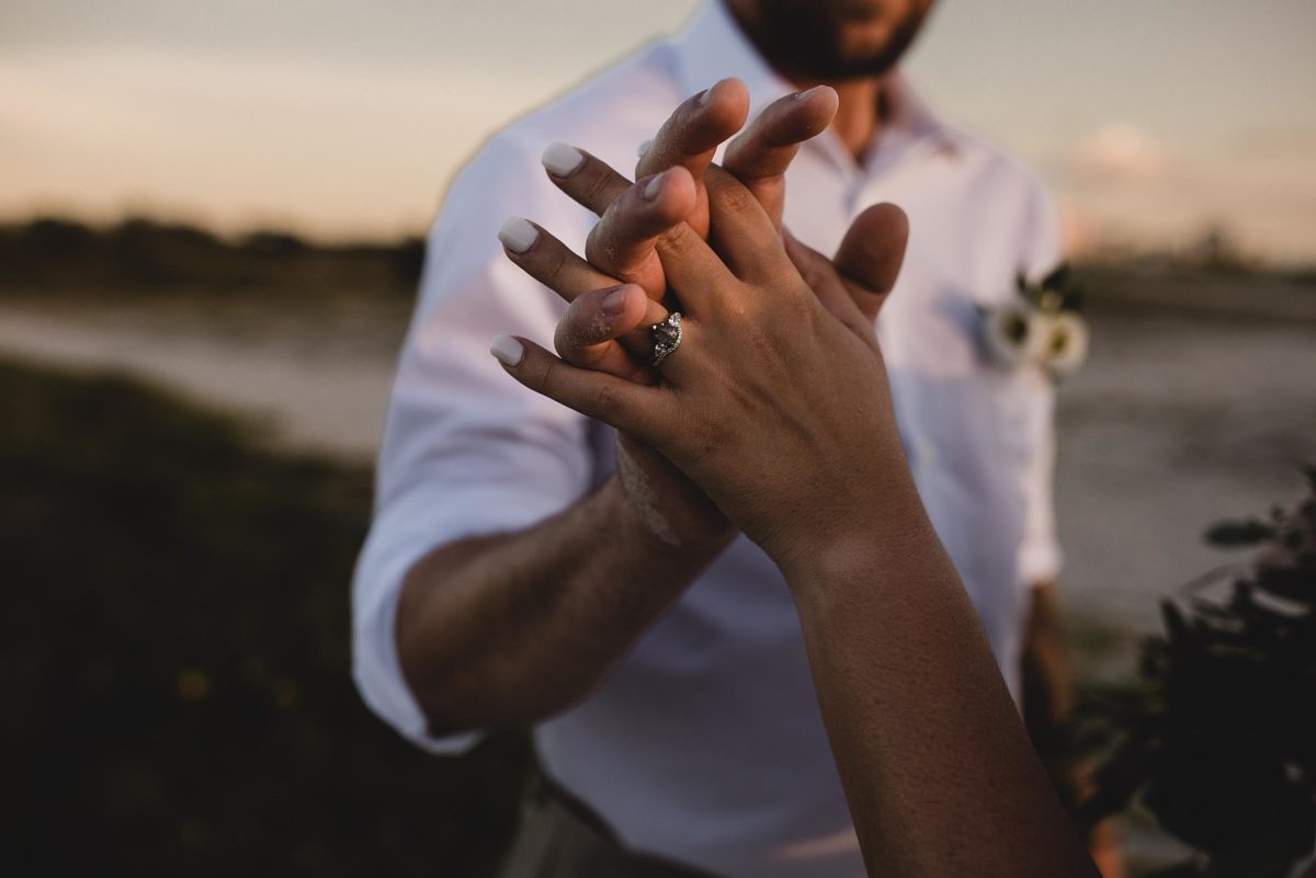 close up of engagement ring, bride and groom holding hands at clearwater beach elopement photographed by juliana montane photography