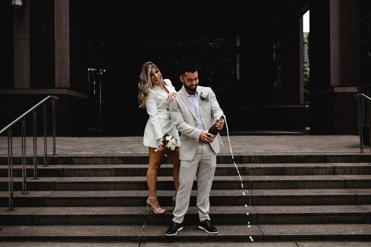 bride & groom popping a bottle of champagne at downtown atlanta elopement photographed by juliana montane photograhy