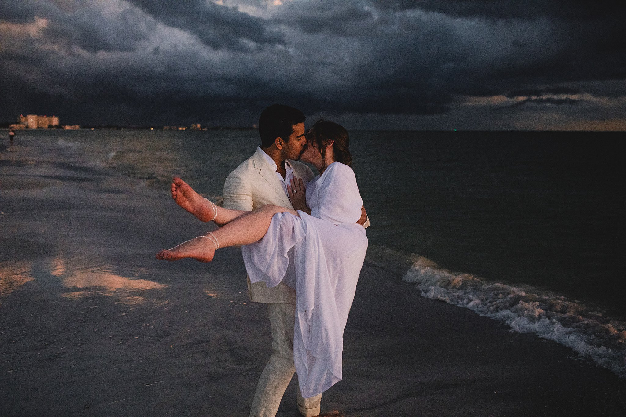 man holding woman at the beach during sarasota engagement photo session photographed by juliana montane photography