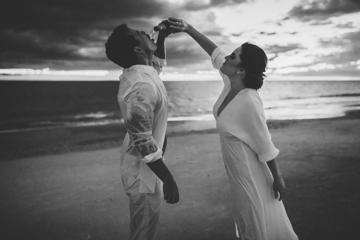 couple drinking champagne on the beach, sarasota engagement photo session photographed by juliana montane photography