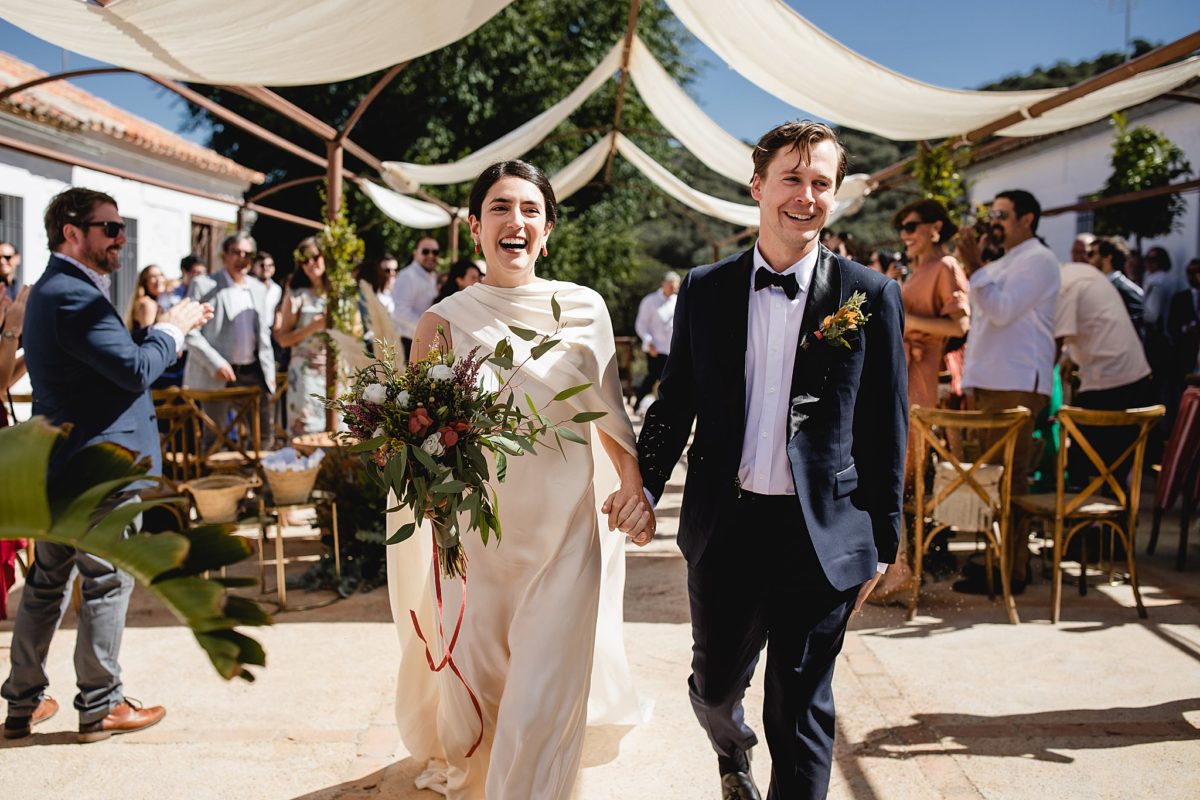 happy couple walking down the aisle after getting married at a ceremony setup at destination wedding in córdoba spain photographed by juliana montane photography
