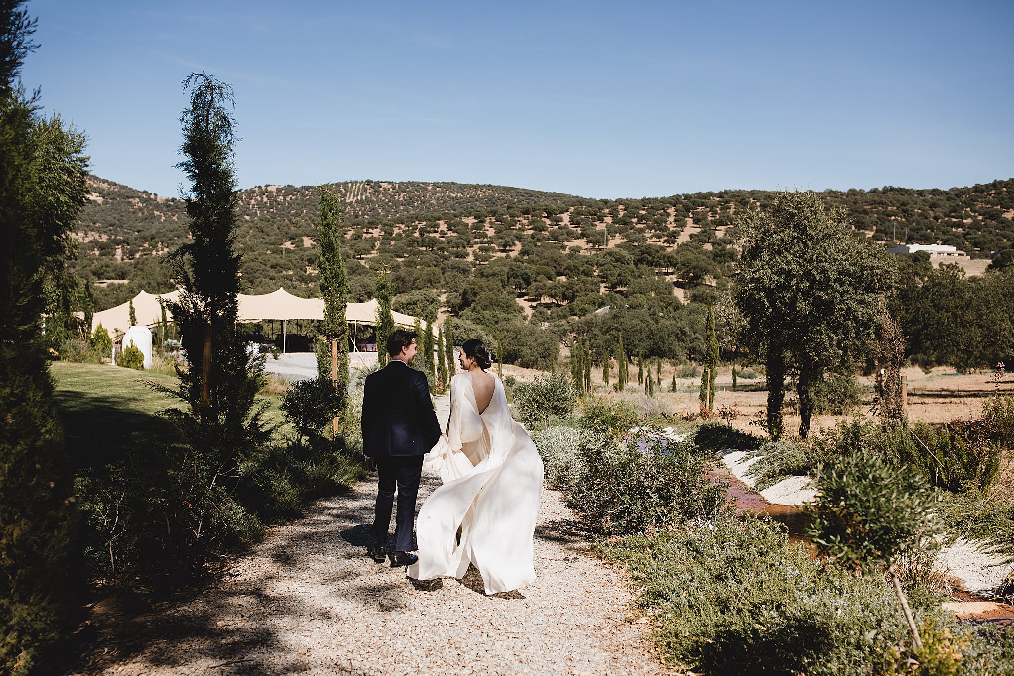 bride & groom walking outside with mountains in the background at ceremony setup at destination wedding in córdoba spain photographed by juliana montane photography