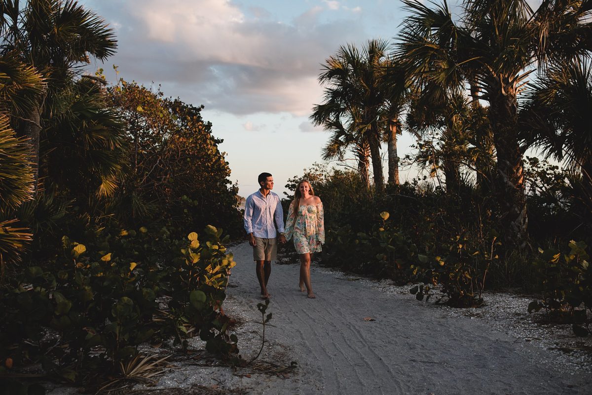 Engaged couple walking, holding hands on caspersen beach in venice florida