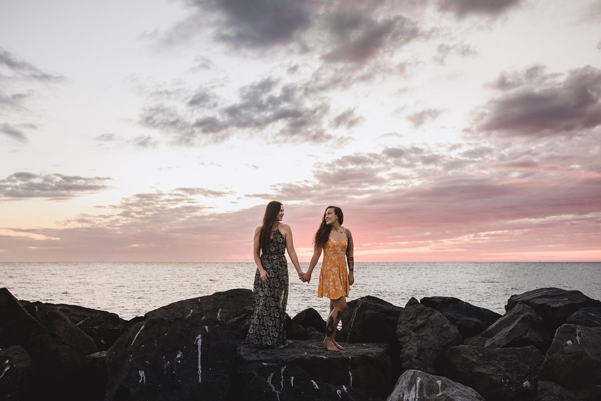 Women posing on rocks on a beach in st pete beach after surprise proposal photographed by Juliana Montane Photography