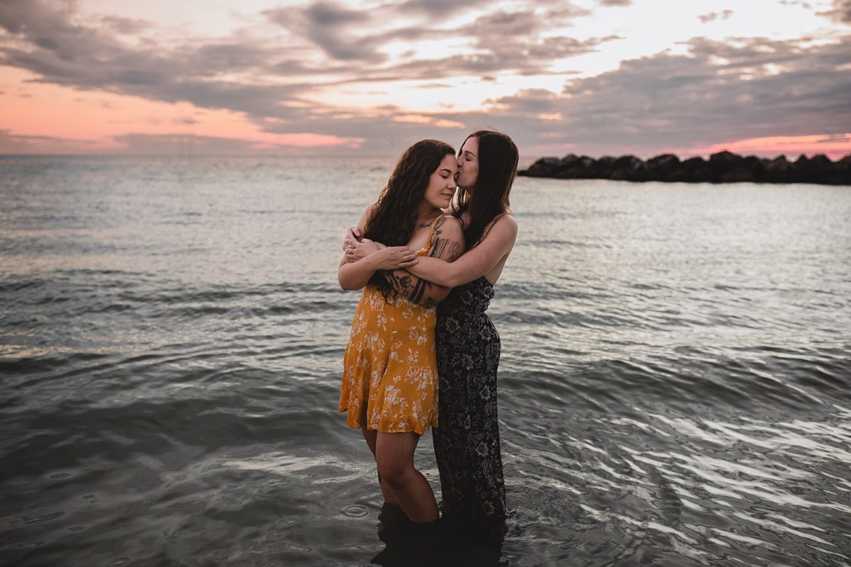 Female couple embracing standing in the water at st pete beach during engagement session