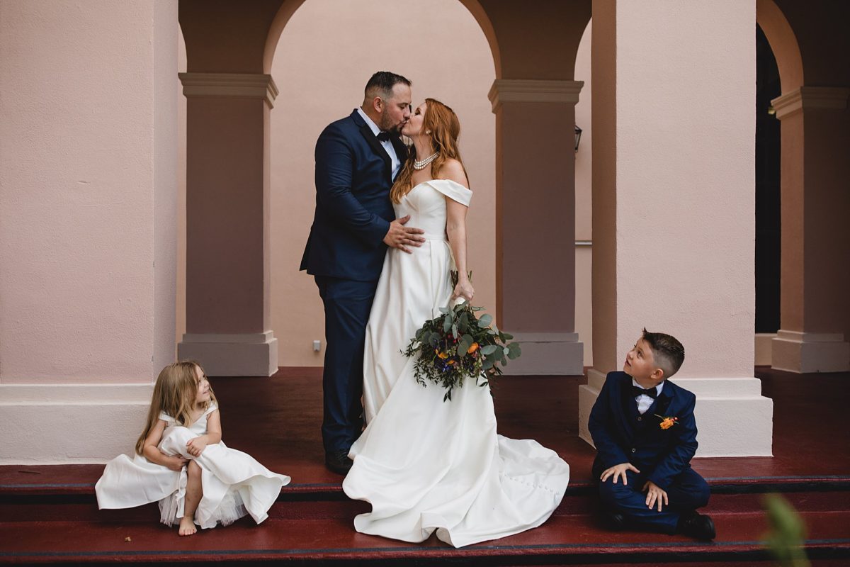 Bride & groom kissing while their kids watch after sarasota ceremony, photographed by juliana montane photography