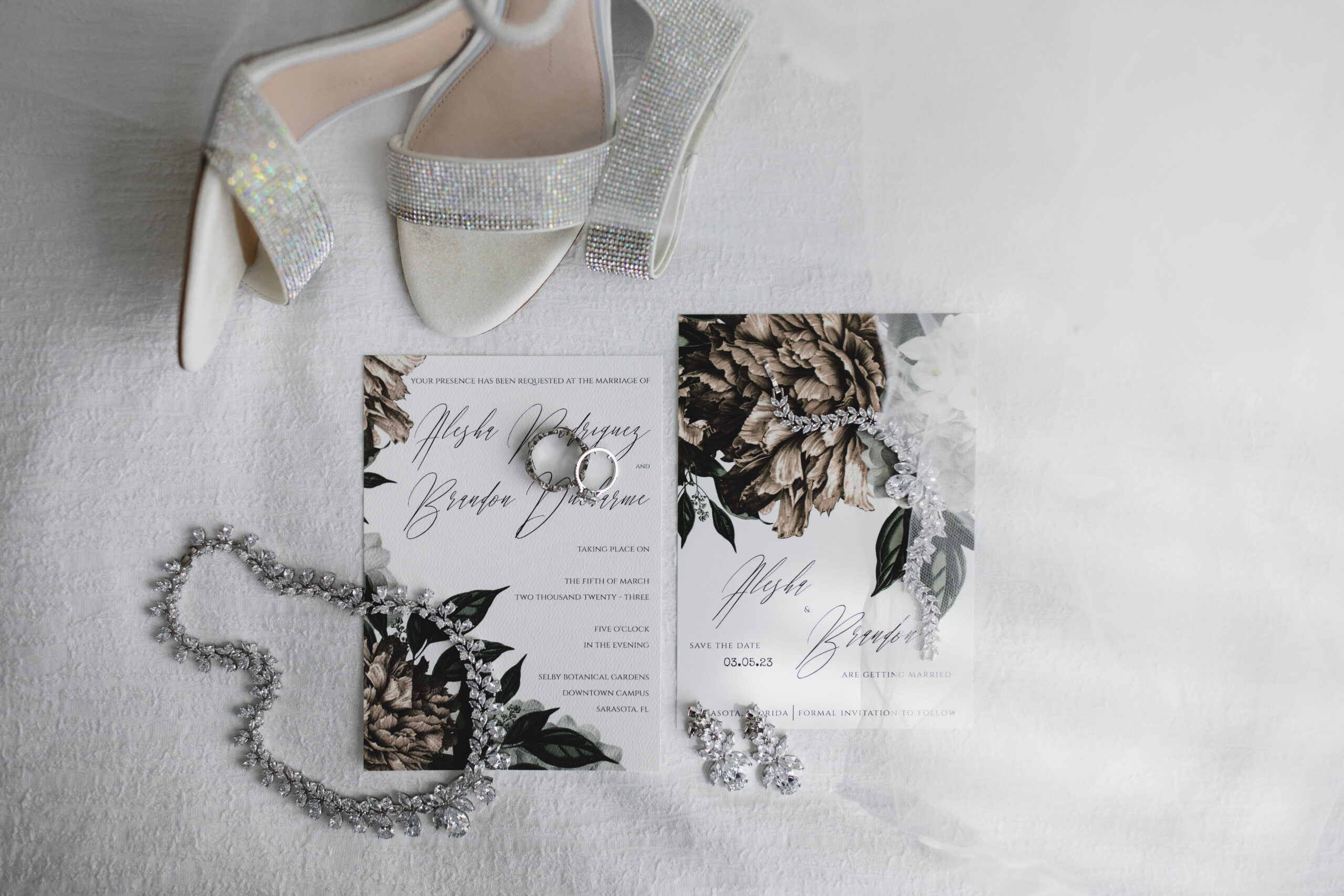 flat lay photo bride's jewelry, wedding invitation, shoes and veil on wedding day in sarasota florida photographed by juliana montane photography