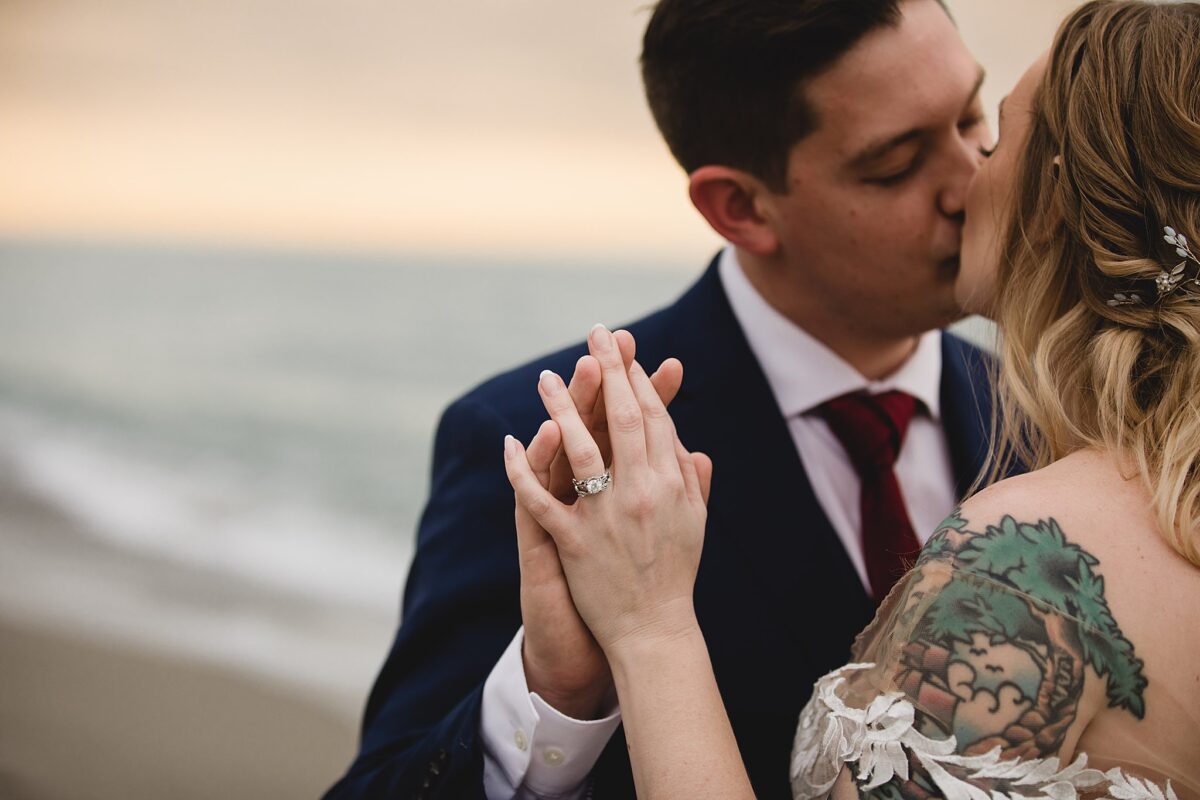 Close up photo of bride's wedding ring while married couple kisses on beach at turtle beach in sarasota fl, wedding photography by juliana montane photography