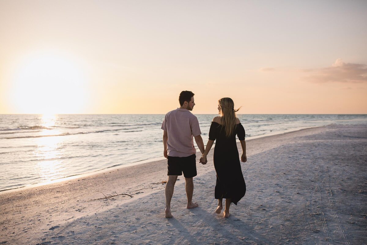 Couple walking down the beach after getting engaged on siesta key beach in sarasota florida photographed by Juliana Montane Photography
