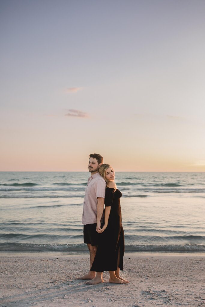 Couple posing back to back after getting engaged on siesta key beach in sarasota florida photographed by Juliana Montane Photography