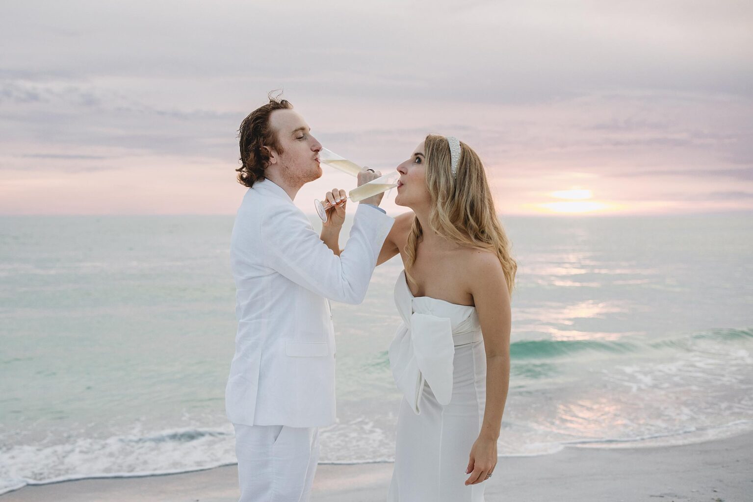 bride and groom drinking champagne on the beach after their sarasota courthouse elopement