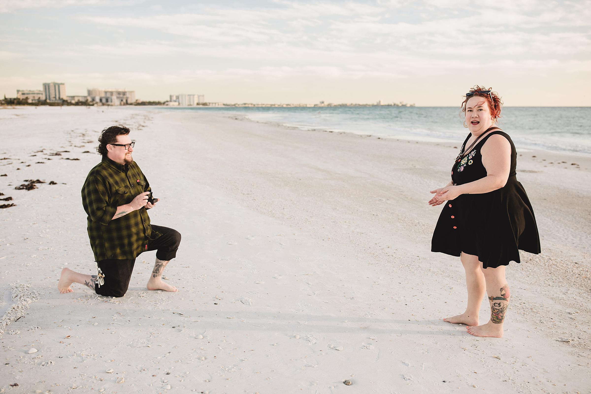 Woman looking shocked as her boyfriend proposes to her on the beach in Sarasota. Photographed by Juliana Montane Photography.