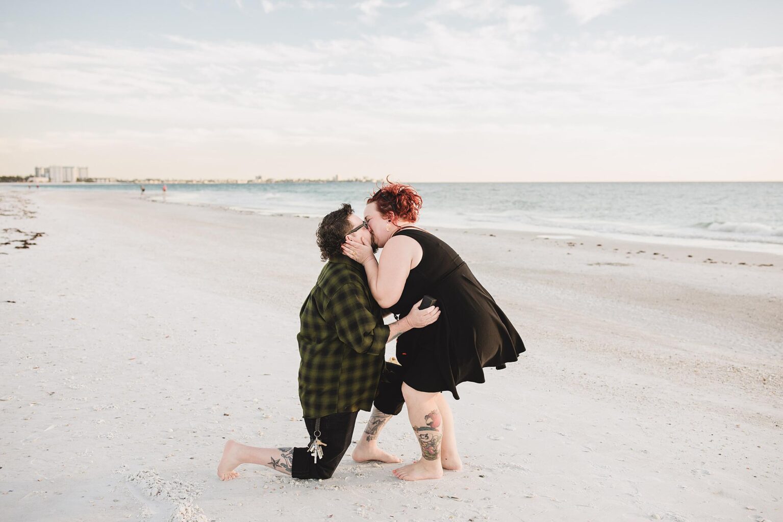 Couple kissing after man proposes to his girlfriend on the beach with the ocean in the background. Photographed by Juliana Montane Photography.