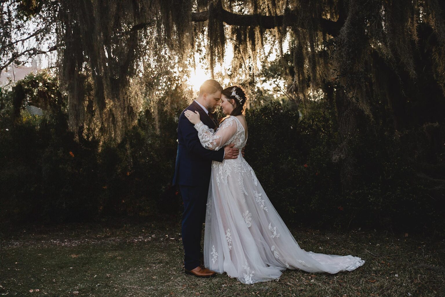 Bride and Groom embracing in sunlit forest in sarasota. Photographed by Juliana Montane Photography.