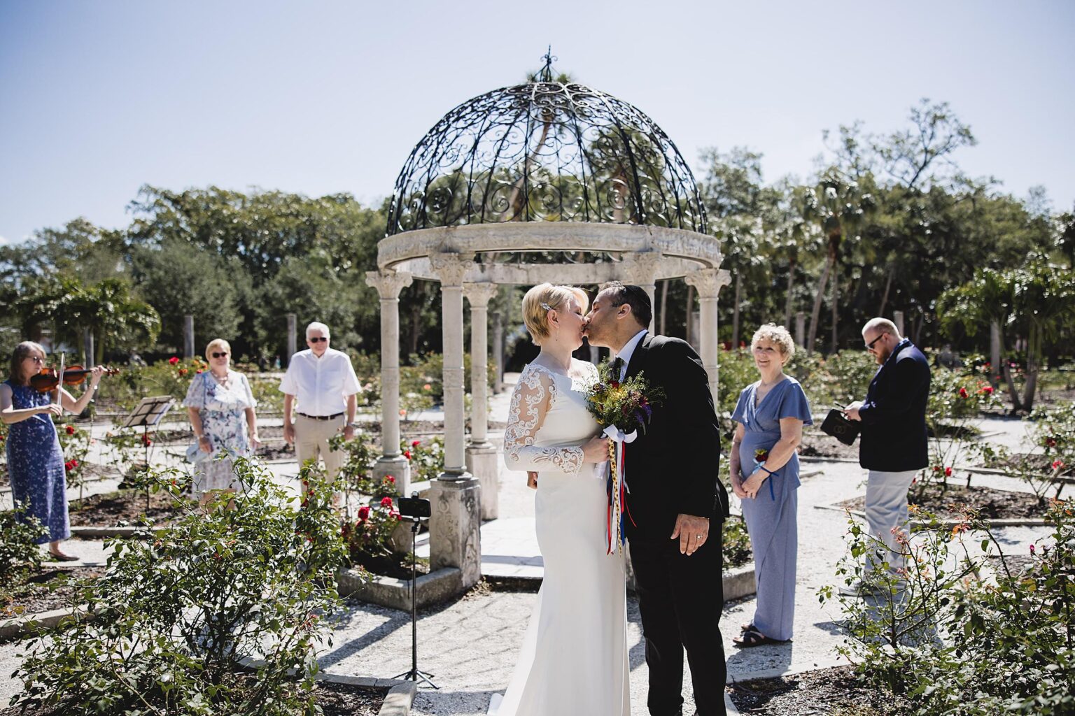 Couple kissing after ceremony in the rose garden at their intimate ringling museum wedding. Photographed by Juliana Montane Photography.