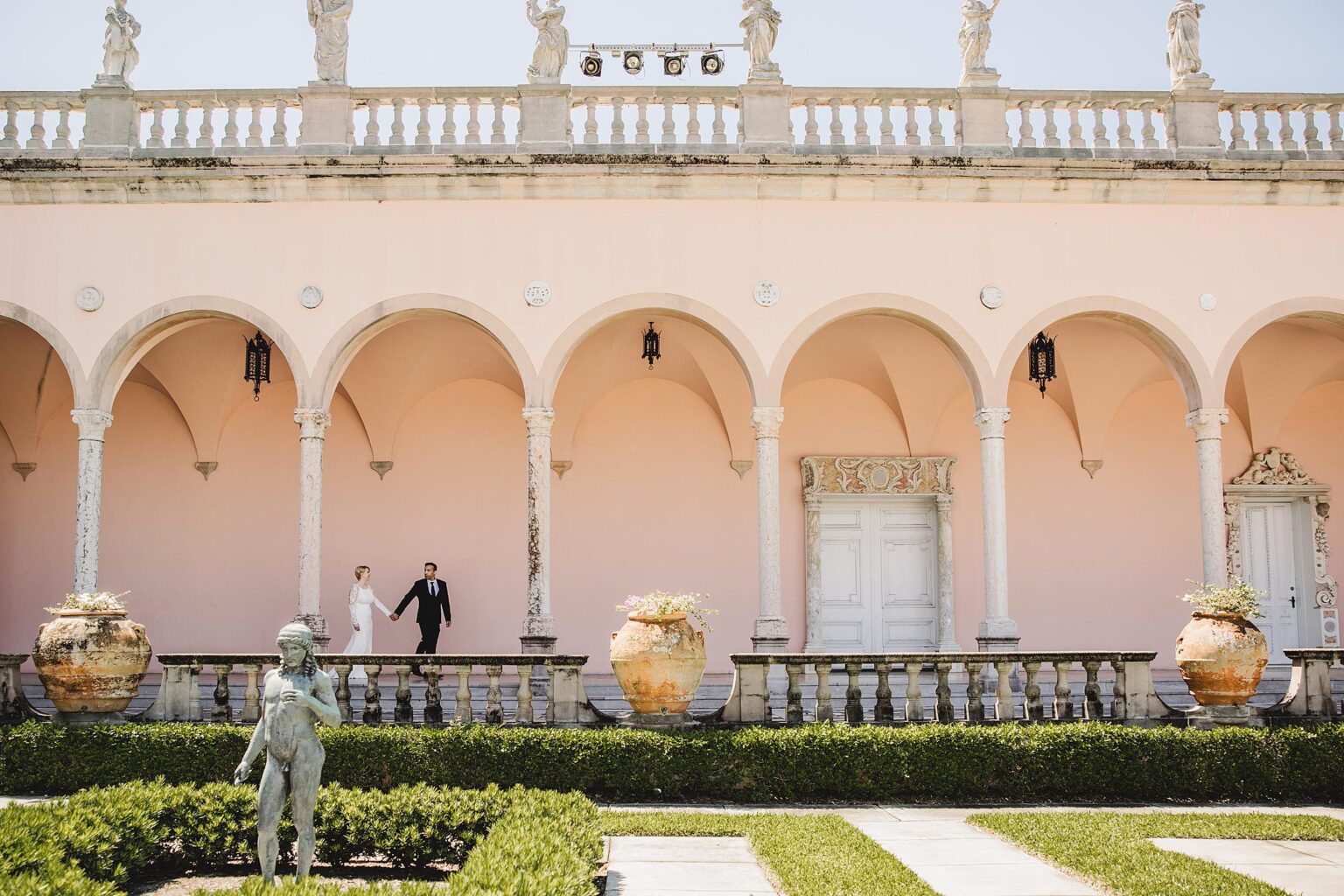 Bride & Groom walking through the courtyard of the John Ringling Museum. Photographed by Juliana Montane Photography.