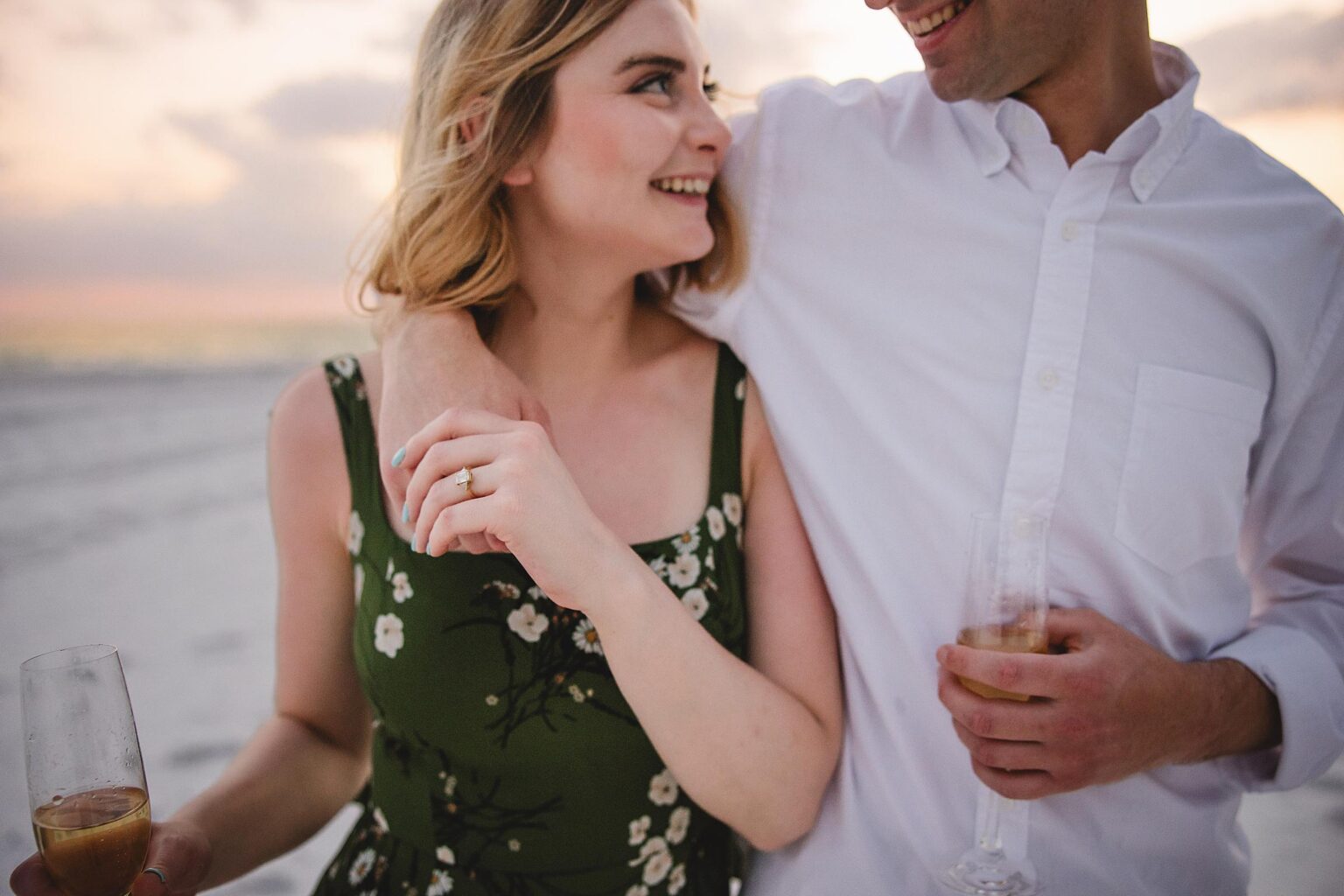 Couple with arms around eachother, close up of engagement ring on woman's hand. Photographed by Juliana Montane Photography.