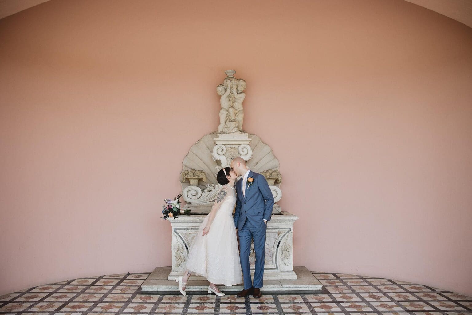 Bride & Groom kissing in the pink courtyard at Ringling Museum in Sarasota Florida photographed by Juliana Montane Photography