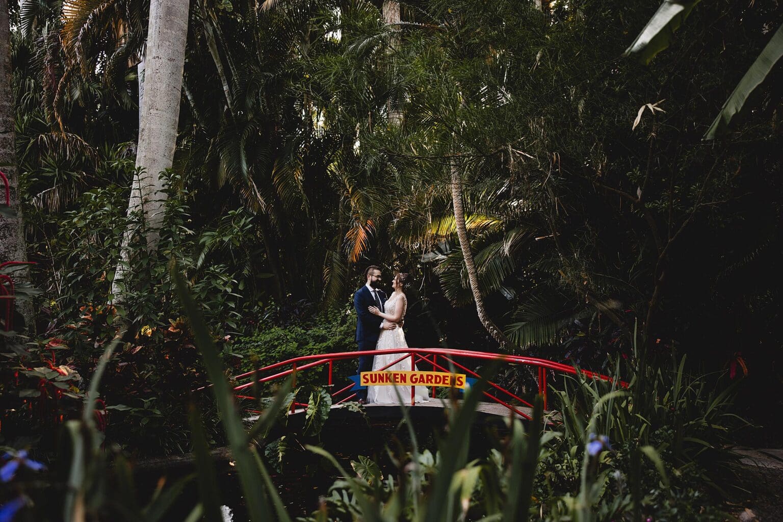 Bride & Groom posing on bridge at a Sunken Gardens Wedding in St. Petersburg, FL photographed by Juliana Montane Photography