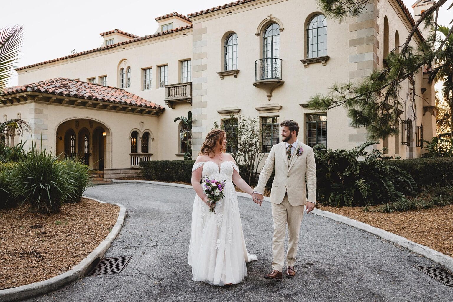 Bride and Groom walking hand in hand in front of Powel Crosley Mansion on their wedding day in Sarasota, FL photographed by Juliana Montane Photography